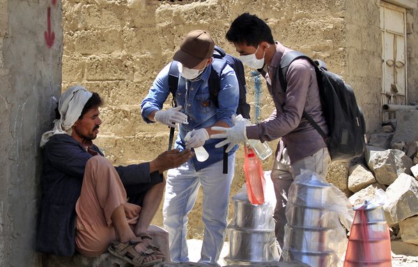 Yemeni volunteers spray disinfectant on the hands of a man in one of Sanaa's impoverished neighbourhoods on March 30th amid concerns of a coronavirus outbreak. [Mohammed Huwais/AFP]