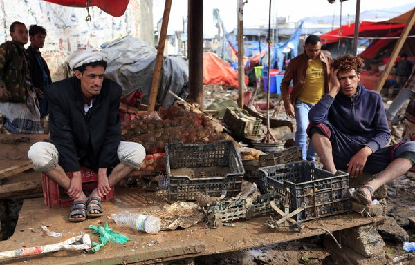 باعة يمنيون ينظرون إلى أكشاكهم التي دمرتها السيول بعد هطول أمطار غزيرة في صنعاء في 14 نيسان/أبريل. [محمد حويس/وكالة الصحافة الفرنسية]