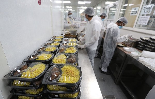 Qatar charity workers package meals  on April 16th to be distributed to Doha's migrant workers who are under quarantine. [Karim Jaafar/AFP]