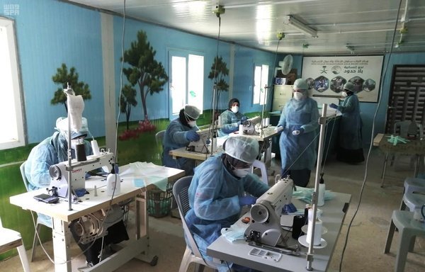 Workers and volunteers at King Salman Humanitarian Aid and Relief Centre sew masks to be distributed in the kingdom. [Photo courtesy of Saudi Press Agency]