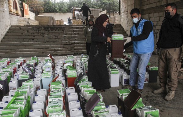 A Syrian refugee receives sanitisation and cleaning supplies from a representative of the UNHCR in the city of Sidon in southern Lebanon, on March 20th. [Mahmoud Zayyat/AFP]