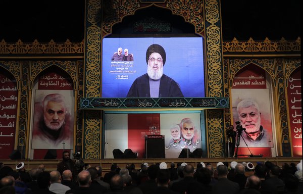 Hizbullah supporters watch as Hizbullah chief Hasan Nasrallah delivers a speech on a screen in Beirut's southern suburbs on January 5th, after top Iranian general Qassem Soleimani was killed in Baghdad. [Anwar Amro/AFP]