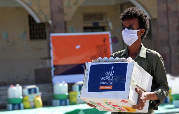 A man wearing a protective mask receives humanitarian aid in Taez on May 8th, amid the novel coronavirus pandemic crisis. [Ahmad al-Basha/AFP]