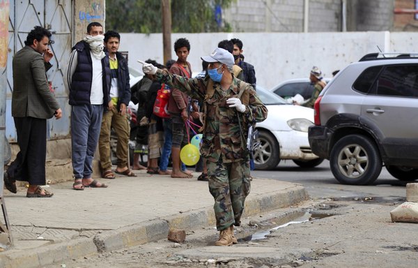 A member of the Houthis, wearing a protective mask and gloves, disperses a crowd in Sanaa on May 6th, as part of an effort to curb the spread of coronavirus. [Mohammed Huwais/AFP]