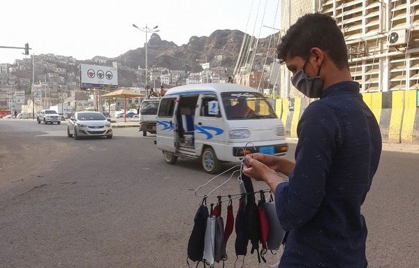 A mask-clad youth sells masks on a street in Yemen's city of Aden on May 17th, amid fears that coronavirus is spreading unhindered in the Yemeni city. Deaths in Aden have surged to five or even seven times higher than normal, an NGO and medics say. [Nabil Hasan/AFP]