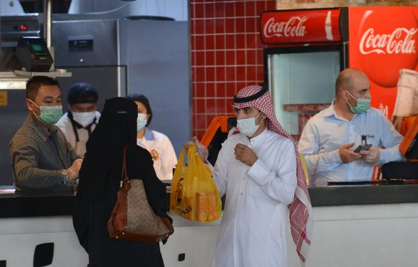 A couple collects an order from a restaurant in a shopping mall in the Saudi capital Riyadh on June 4th after it reopened following the easing of some restrictions put in place by the authorities in a bid to stem the spread of the novel coronavirus. [Fayez Nureldine/AFP]