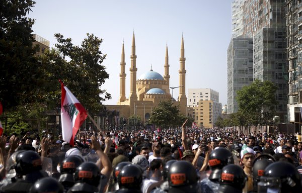 Lebanese riot police stand guard in front of protestors during a demonstration in central Beirut, on June 6th. Protestors poured into the streets of the Lebanese capital to decry the collapse of the economy, as clashes erupted between supporters and opponents of the Iran-backed militia Hizbullah. [Patrick Baz/AFP]