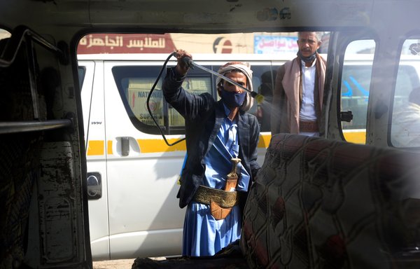 عامل يمني يرش رذاذا معقما في 10 حزيران/يونيو، داخل حافلة للنقل العام في صنعاء خلال أزمة فيروس كورونا. [محمد حويس/وكالة الصحافة الفرنسية]