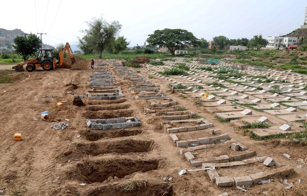 عمال يمنيون يستخدمون حفارة لحفر قبور في قطعة أرض في مقبرة بتعز خصصت لضحايا كوفيد-19، في 14 حزيران/يونيو. [أحمد الباشا/وكالة الصحافة الفرنسية]