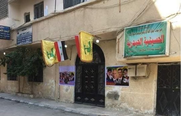 Hizbullah flags hang outside a religious establishment in the Sayyida Zainab area in the Syrian capital, Damascus. [Photo via Iranian Militia Violations in Syria Facebook page]