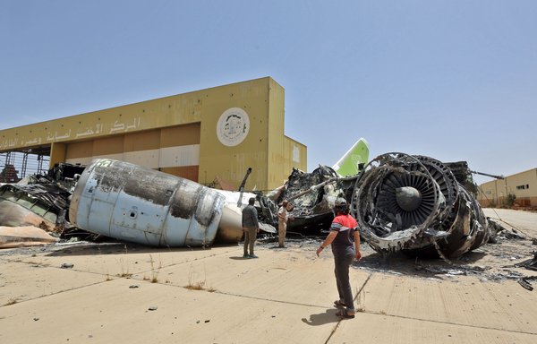 Fighters loyal to the UN-recognised Libyan Government of National Accord (GNA) look at the remains of an airplane destroyed by Moscow-backed forces at Tripoli International Airport on June 4, 2020. [Mahmud TURKIA / AFP]