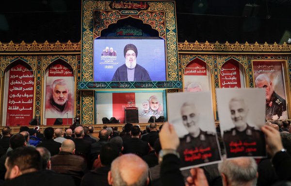 Supporters of Hizbullah hold posters of slain Iranian general Qassem Soleimani as the movement's leader Hassan Nasrallah delivers a speech on a screen, in Beirut's southern suburbs, on January 5th. [Anwar Amro/AFP]