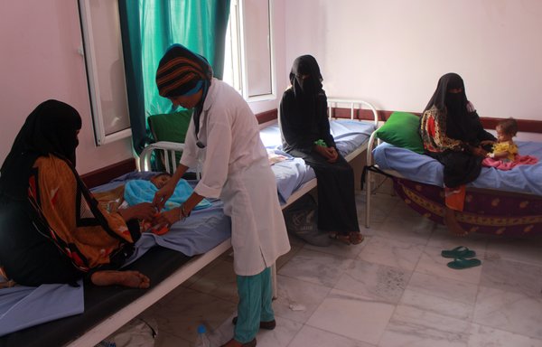 طبيبة تفحص طفلا يمنيا يعاني من سوء التغذية في مركز صحي بمحافظة حجة شمالي اليمن، يوم 5 تموز/يوليو. [عيسى أحمد/وكالة الصحافة الفرنسية]