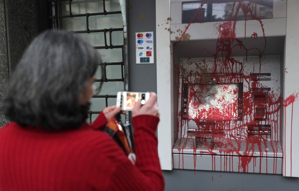 In this file photo taken January 15th a woman photographs an ATM machine that was vandalised the previous night by protestors in Beirut, as Lebanon grapples with its worst economic crisis since the civil war. [Anwar Amro/AFP]