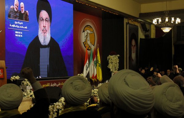 Hizbullah supporters watch as Hassan Nasrallah delivers a speech on a screen in the southern Lebanese city of Nabatieh on January 12th. [Mahmoud Zayyat/AFP]