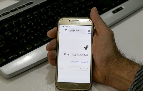 A man holds a smartphone connected to a Wifi network without internet access at an office in the Iranian capital Tehran on November 17th, 2019. Access to the internet was restricted when demonstrations broke out two days prior, and was restricted again on Thursday (July 16th) during new protests. [Atta Kenare/AFP]