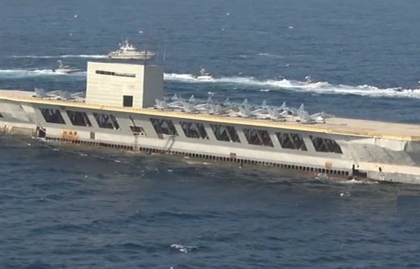 Iranian forces targeted this replica US aircraft carrier with missiles during a recent military exercise that has been widely regarded as provocative. [Screenshot from a Fars News video]