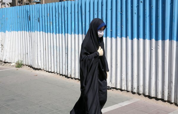 An Iranian woman, wearing a protective face mask, walks down a street in Tehran on July 22nd, during the COVID-19 pandemic. [Atta Kenare/AFP]