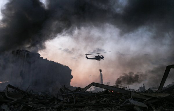 A helicopter puts out a fire at the scene of an explosion at the port of Lebanon's capital Beirut on August 4th. [STR/AFP]