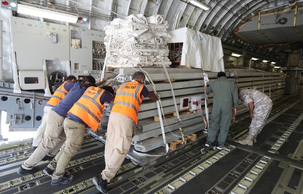 Workers load a plane as Qatar begins sending field hospitals and medical aid to Lebanon from al-Udeid airbase on August 5th on the outskirts of Doha. [Karim Jaafar/AFP]