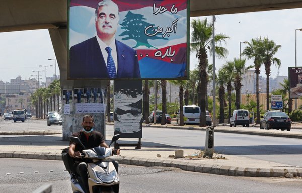 A man rides a motorbike past a billboard bearing a picture of slain Lebanese Prime Minister Rafic al-Hariri, on a street in Sidon, his hometown, on August 18th. [Mahmoud Zayyat/AFP]