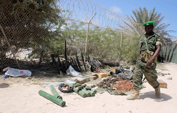 A soldier of the African Union's AMISOM force walks past weapons seized after heavy fighting early on August 15th, 2014, in Mogadishu as African Union troops backed government forces in the battle to seize weapons from a local militia. [Abdulfitah Hashi Nor/AFP]