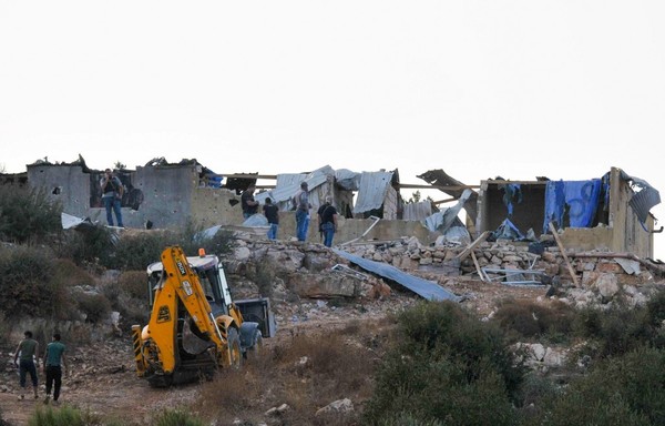 عناصر من قوى الأمن الداخلي اللبنانية يتفقدون منزلا مدمرا كان يختبئ فيه أعضاء مشتبه بانتمائهم لداعش قبل مداهمة قامت بها قوات استخبارات الشرطة في منطقة وادي خالد الشمالية على الحدود مع سوريا في 27 أيلول/سبتمبر. [ابراهيم شلهوب / وكالة الصحافة الفرنسية]