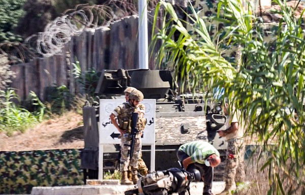 جندي من الجيش اللبناني وضابط سري يتفقدان دراجة بخارية استخدمها مهاجمون مسلحون في هجوم وقع ليلا مما أدى إلى مقتل جنود آخرين شمال طرابلس في 27 أيلول/سبتمبر. [فتحي المصري / وكالة الصحافة الفرنسية]