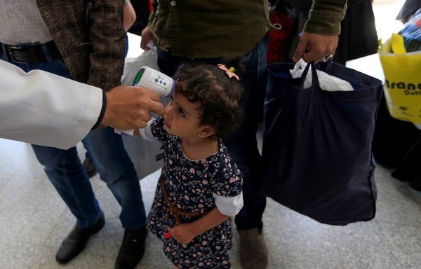 A Yemeni child who was airlifted to Jordan to undergo treatment for critical illnesses earlier this year, gets her temperature checked upon her arrival at the airport in Sanaa, after being flown home aboard a UN plane, on October 4th. [Mohammed Huwais/AFP]
