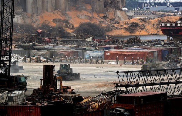 Lebanese army members walk in line amidst clean-up efforts near the damaged grain silos at the port of Beirut on September 1st, almost a month after a monster explosion which ravaged Lebanon's capital. [Anwar Amro/AFP]