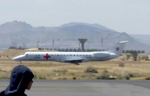 Released prisoners walk toward a plane of the International Committee of the Red Cross on the tarmac of an airport in Yemen's government-held city of Seiyun, in the eastern province of Hadramaut, as the war-torn country begins swapping 1,000 prisoners in a complex operation overseen by the ICRC. [AFP]