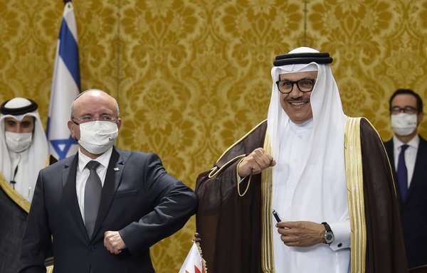 Israel's National Security Advisor Meir Ben Shabbat bumps elbows with Bahraini Foreign Minister Abdullatif bin Rashid al-Zayani after a signing ceremony in Manama on October 18th, as US Treasury Secretary Steve Mnuchin looks on. [Mazen Mahdi/AFP]