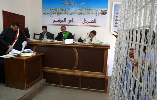 A Yemeni judge and court officials attend the trial of suspected Houthis standing behind bars at the state-security court in Sanaa on January 17th, 2010. [Ahmad Gharabli/AFP]