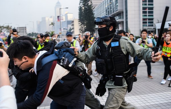 A police officer attempts to detain a man during a rally held in Hong Kong on December 22, 2019, to show support for the Uighur minority in China. Hong Kong riot police broke up the solidarity rally as the city's pro-democracy movement likened its plight to that of the oppressed Muslim minority. [Anthony WALLACE / AFP]