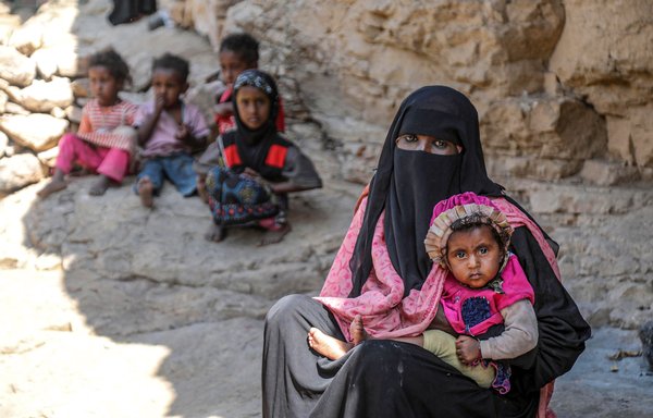A Yemeni family sits outside a cave where they sought refuge due to poverty and lack of housing, west of Taez on December 2, 2020. [AHMAD AL-BASHA / AFP]