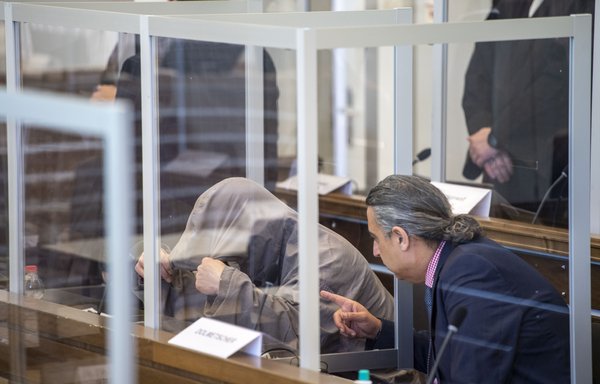 Syrian defendant Eyad al-Gharib (left) hides himself under his hood prior to a trial against two Syrian defendants accused of state-sponsored torture in Syria, on April 23, in Koblenz, western Germany. [Thomas Lohnes / AFP / POOL]