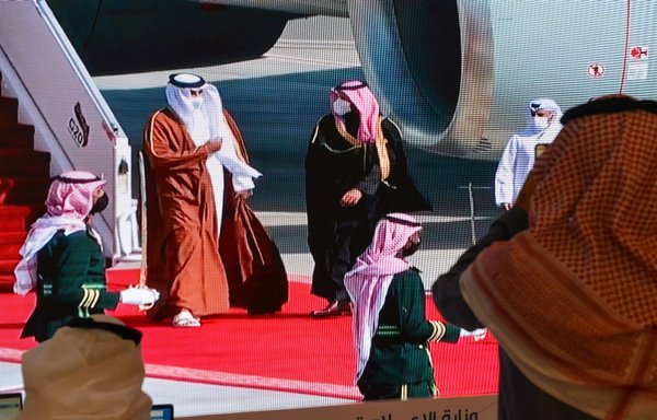 Journalists watch as Saudi Crown Prince Mohammed bin Salman (centre right) welcomes the Emir of Qatar Tamim bin Hamad Al-Thani (centre left), on a screen in the media centre ahead of the 41st Gulf Co-operation Council summit in the Saudi city of al-Ula on January 5. [Fayez Nureldine/AFP]
