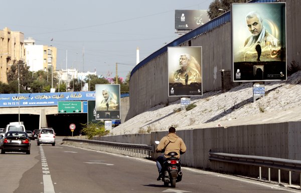 Portraits of late IRGC Quds Force commander Qassem Soleimani and Iraqi PMF commander Abu Mahdi al-Muhandis are seen along the highway leading to Beirut's southern suburbs on December 31. [Anwar Amro/AFP]