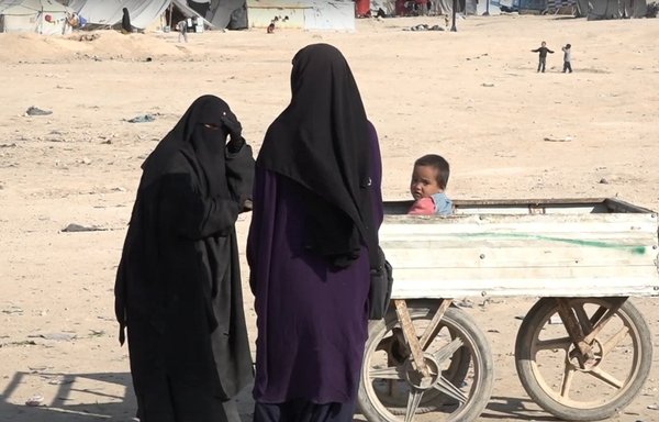 Two ISIS women are seen with a child in a cart in al-Hol camp in Syria's al-Hasakeh province. [Video screenshot/Hawar News Agency]