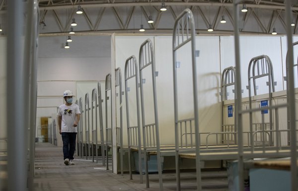 A worker walks past bed frames as workers demolish installations at Wuhan's largest makeshift hospital built to treat patients infected by  COVID-19 last July 29. [STR/AFP]