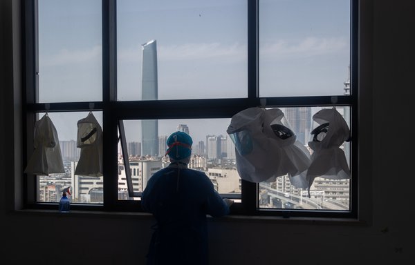 A medical worker looks out from the window of a changing room after treating COVID-19 patients at a hospital in Wuhan, China, last March 19 amid the deadly global pandemic the Chinese regime would like the world to forget. [STR/AFP]