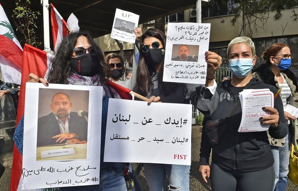 Protesters hold pictures of slain Lebanese activist and intellectual Lokman Slim, who was known for his anti-Hizbullah stance, during a rally in front of the Justice Palace in Beirut, on February 4, the same day he was found dead in his car. [STR/AFP]