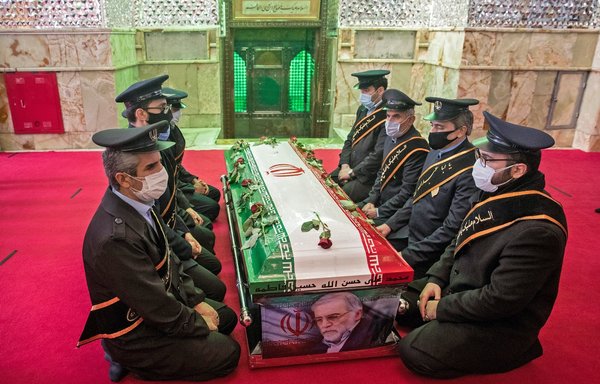 Members of Iranian forces pray around the coffin of slain nuclear scientist Mohsen Fakhrizadeh during the burial ceremony at Imamzadeh Saleh shrine in Tehran on November 30. [Hamed Malekpour/Tasnim News/AFP]