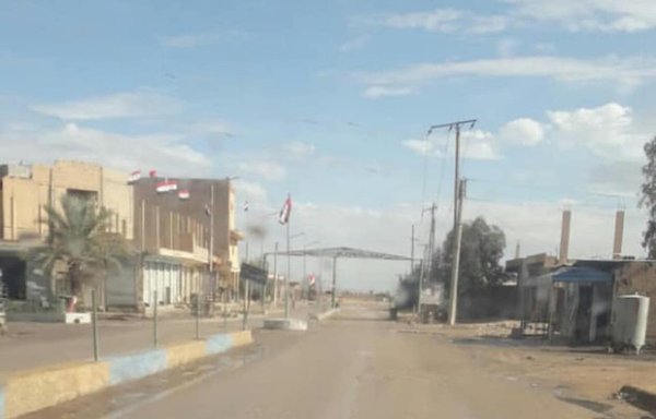 A security post of the IRGC-affiliated 47th Regiment militia flies the Syrian flag at the entrance to the city of al-Mayadeen. [Ein al-Furat]