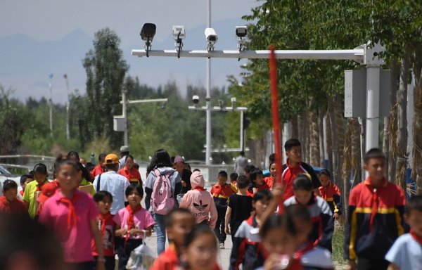 تلاميذ يمشون تحت كاميرات المراقبة في مقاطعة اقتوو بمنطقة شينجيانغ الصينية يوم 4 حزيران/يونيو 2019. [غريغ بيكر/وكالة الصحافة الفرنسية]