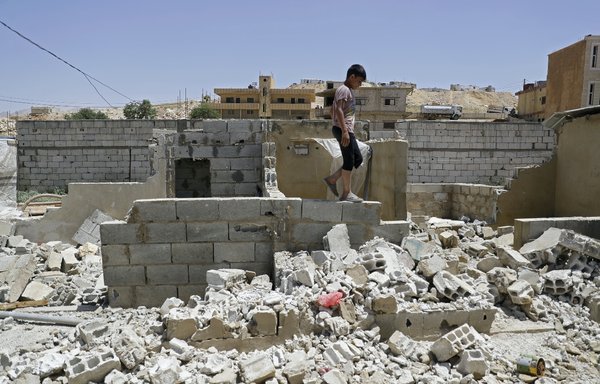 A Syrian boy walks among demolished shelters at a refugee camp in Arsal, Lebanon, on June 10, 2019. ISIS elements are reportedly using such areas as hiding places. [Joseph Eid/AFP]