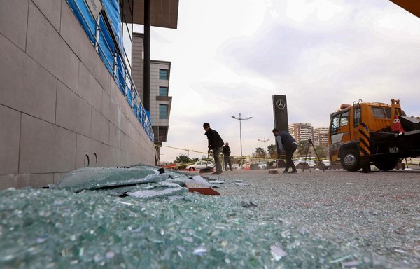 A worker cleans shattered glass on February 16 outside a damaged shop following a rocket attack the previous night in Erbil, the capital of the Kurdish autonomous region in northern Iraq. [Safin Hamed/AFP]