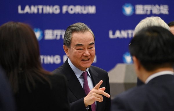 وزير الخارجية الصينية وانغ يي يتحدث مع أحد الضيوف بعد حفل افتتاح منتدى لانتينغ حول العلاقات الصينية-الأميركية في بكين يوم 22 شباط/فبراير. [غريغ بيكر/وكالة الصحافة الفرنسية]