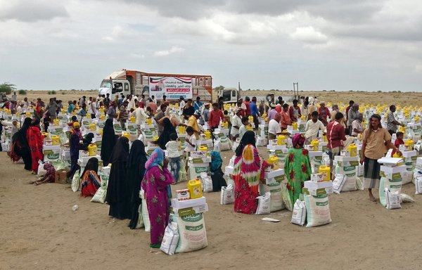 Displaced Yemenis receive food aid donated by a Kuwaiti charity in the village of Hays in al-Hodeidah province on February 22. [Khaled Ziad/AFP]
