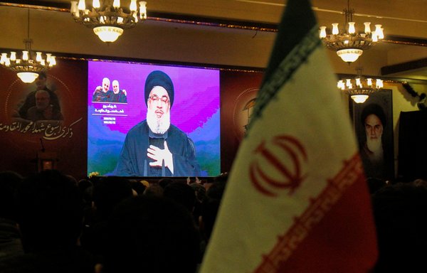 Lebanese look on as Hassan Nasrallah delivers a speech on a screen in the southern Lebanese city of Nabatieh on January 12, 2020. [Mahmoud Zayyat/AFP]